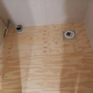Nylagt plywoodgolv i ett badrum med golvbrunnen urtagen